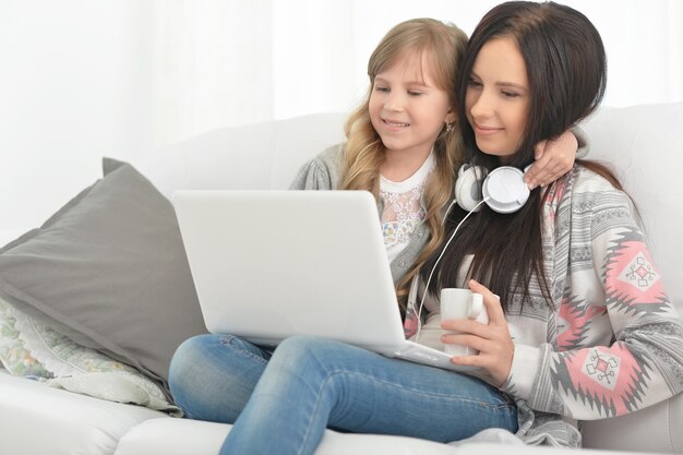 Portrait of happy mother and daughter using laptop