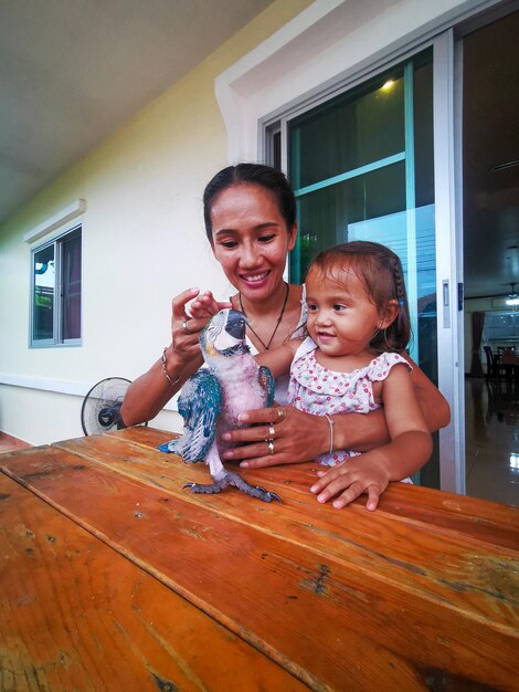 Portrait of happy mother and daughter with an blue gold macaw