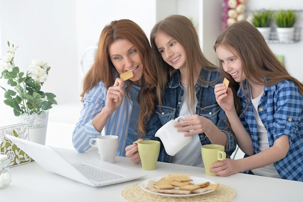 Portrait of a happy mother and daughters with laptop