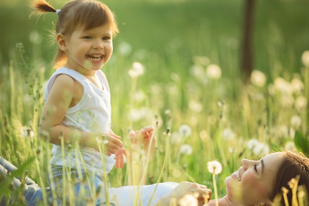 Portrait of happy mother and her little child in spring. Cheerful family at dandelion field.Mom and her cute daughter outdoors.