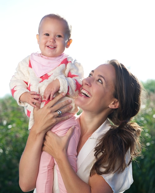 Portrait of a happy mother holding cute baby outdoors