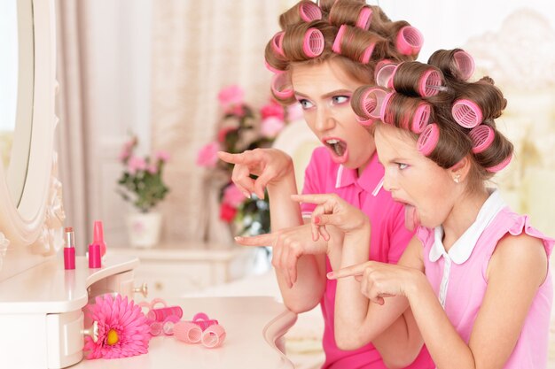 Portrait of happy  Mother and little daughter in hair curlers near mirror