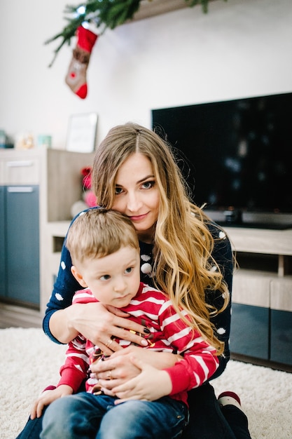 Il ritratto della madre e del figlio felici celebrano il natale. vacanze di capodanno. bambino con la mamma nella stanza addobbata a festa con albero di natale e decorazioni.