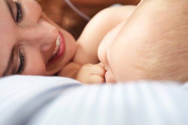 Portrait of a happy mother with baby on bed