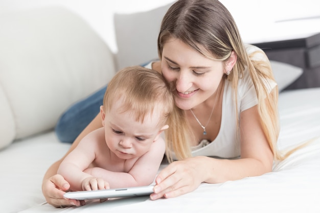 Portrait of happy mother with baby browsing internet on tablet computer