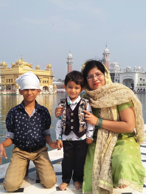 Photo portrait of happy mother with children on pier against temple amidst lake