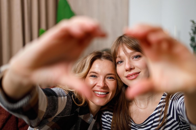 Portrait of happy mother and woman showing heart to camera