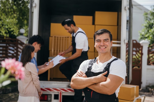 한 초상화에서 행복한 이송업자가 트럭에서 상자를 새 집으로 내리고 있습니다. 이 노동자들은 부드러운 이송과 행복을 보장하는 팀워크를 보여줍니다.