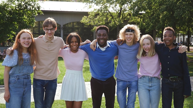 Portrait of happy multiethnic teenage students and teacher embrace and smile at camera