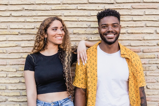 Foto ritratto di una felice coppia multirazziale innamorata che sorride insieme su uno sfondo di mattoni