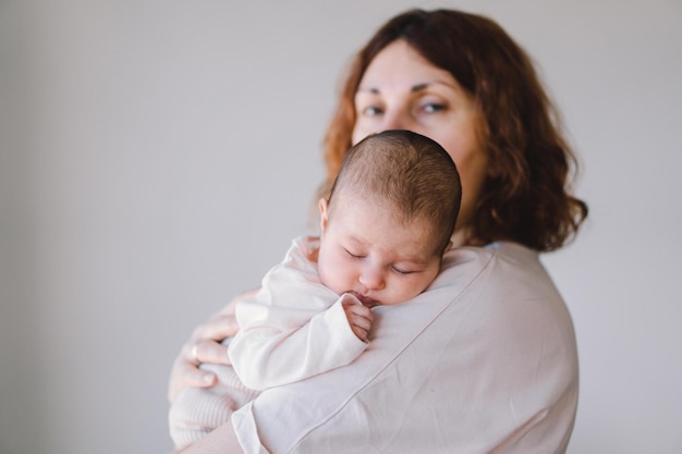 Portrait of happy mum holding infant child on hands Loving mom carying of her newborn baby at home Mother hugging her little 1 months old girl