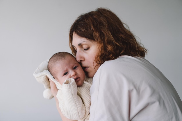 Foto ritratto di mamma felice che tiene il bambino sulle mani mamma amorevole che si prende cura del suo neonato a casa madre che abbraccia la sua bambina di 1 mese