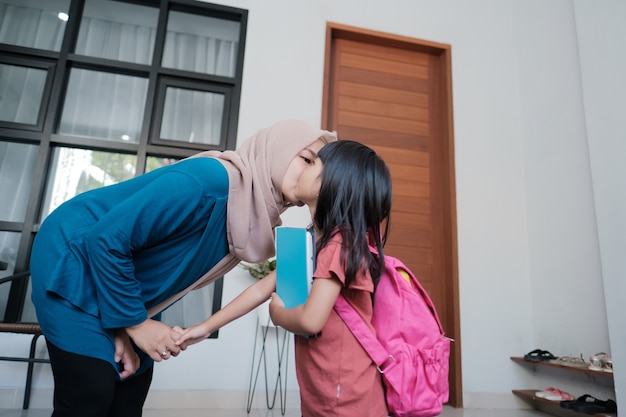 Portrait of happy muslim mother kiss her kid cheek in the morning at home before school day