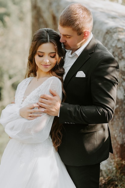 Portrait of happy newlyweds hugging, smiling and looking at each other. Concept of wedding couple