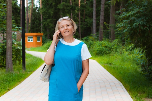 Portrait happy older woman walk on park talking with communicate talk cellphone