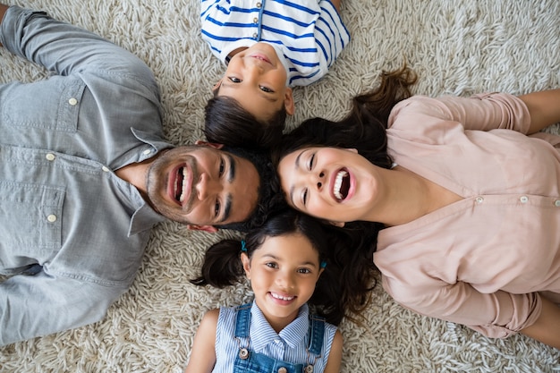 Portrait of happy parents and children lying on rug