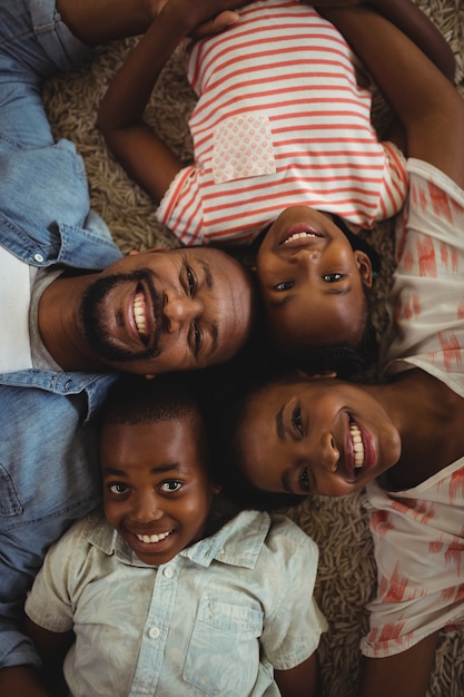 Портрет счастливых родителей и детей, лежащих на ковре