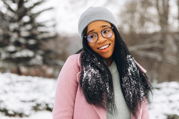 겨울 공원에서 안경과 장갑을 끼고 행복한 긍정적인 소녀 아프리카계 미국인 젊은 여성의 초상화