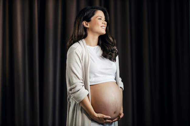 Portrait of a happy pregnant woman holding her belly