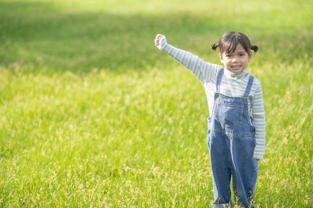 Портрет счастливой красивой девушки ребенка, улыбающейся на открытом воздухе, наслаждаясь теплым солнечным летним днем.