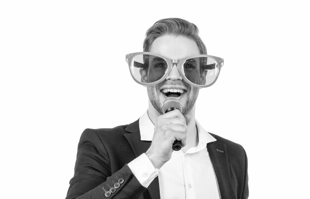 Portrait of happy professional man in funny glasses and formal suit speaking to microphone showman