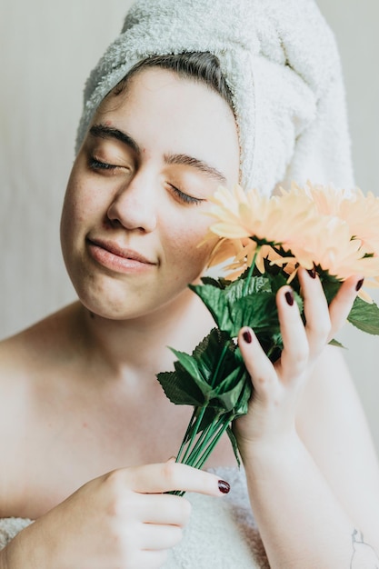 Portrait of happy relaxed charming girl receive flowers wrapped in towel Buying sunflowers herself smiling and laughing joyfully Skincare wellness and healthcare concepts Beauty rituals