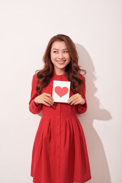 Portrait of happy romantic girl with red paper heart-shaped postcard.