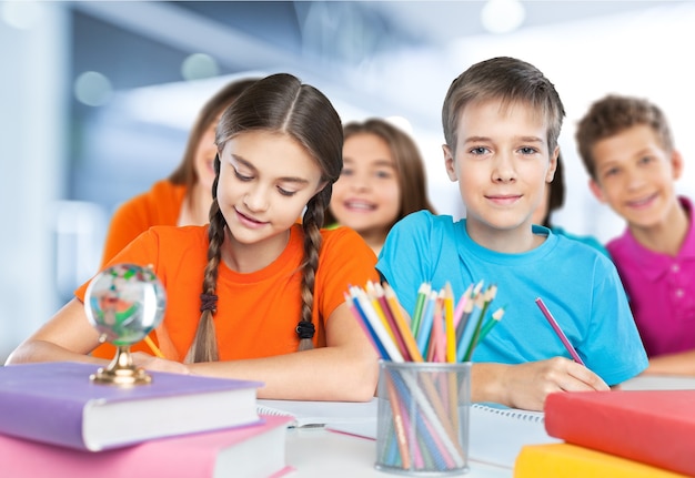 Photo portrait of happy school children drawing with crayons