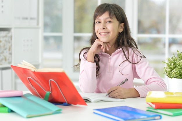 Portrait of happy schoolgirl sitting at desk and studying