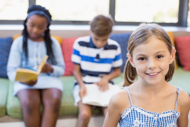 Photo portrait of happy schoolgirl smiling in library