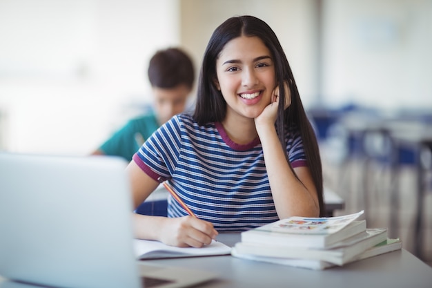 Ritratto di felice studentessa studiando in aula