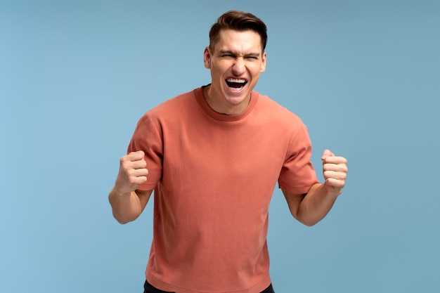 Portrait of happy screaming handsome young man standing with suprised face and rejoicing