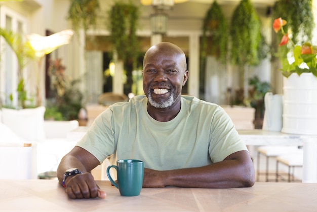portrait of happy senior african american man with cup of coffee having video call. senior lifestyle, technology and domestic life.