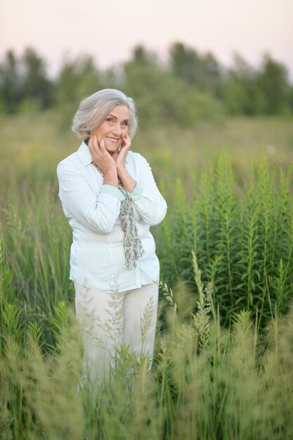 Ritratto di bella donna senior felice che posa nel parco di primavera