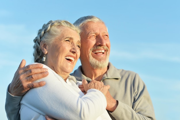 Portrait of happy senior couple hugging against blue sky