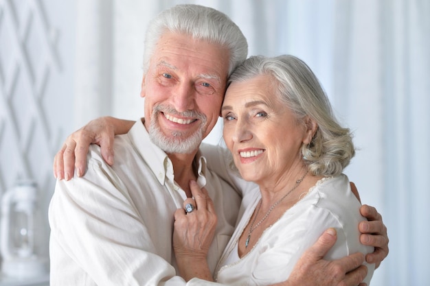 家で抱き締める幸せな年配のカップルの肖像画