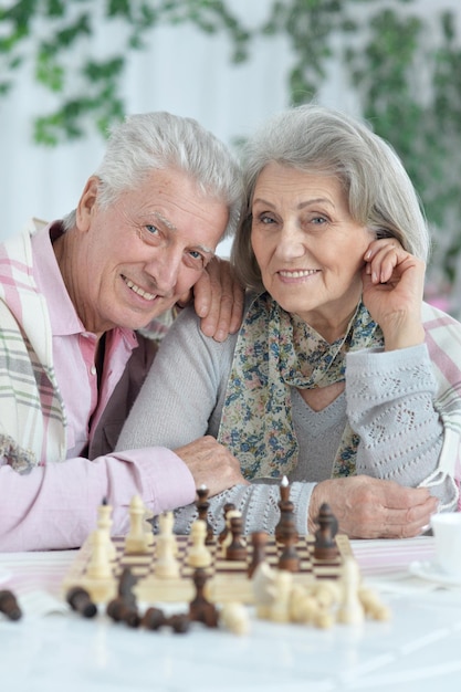 一緒にチェスをしている幸せな年配のカップルの肖像画