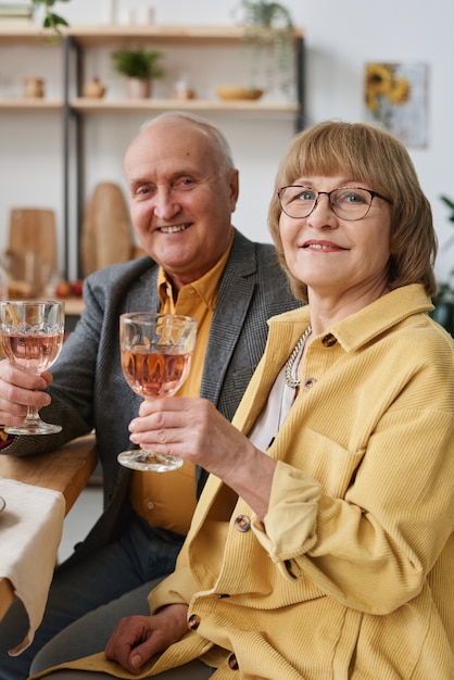 Portrait of happy senior couple smiling at camera while they drinking wine during dinner at the restaurant