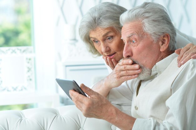 Portrait of happy senior couple using tablet