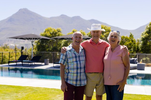 Portrait of happy senior diverse people embracing and smiling in garden, copy space. Senior lifestyle, friendship and relaxation, summer, retirement, unaltered.