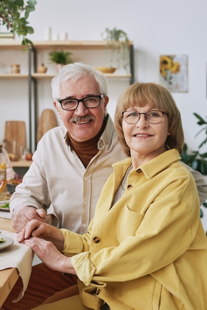 Portrait of happy senior family of two smiling at camera while sitting at dining table