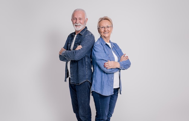 Portrait of happy senior husband and wife with arms crossed standing confidently on white background