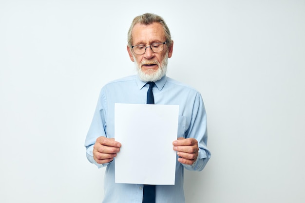 Portrait of happy senior man holding documents with a sheet of\
paper light background