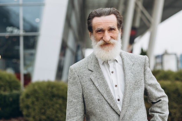 Portrait of happy senior man on the office buildings with copy space