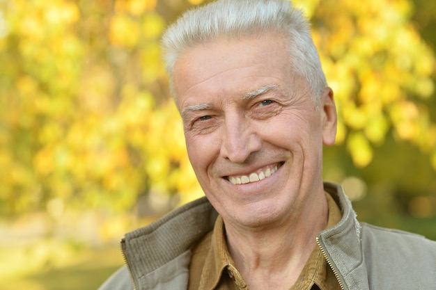 Portrait of happy senior man in the park in autumn