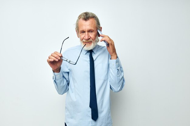Ritratto di uomo anziano felice in una camicia con una cravatta con una vista ritagliata della tecnologia del telefono