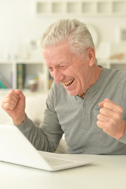 Portrait of happy senior man using laptop