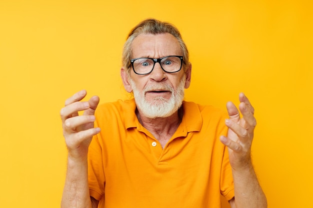 Portrait of happy senior man wearing glasses yellow shirt posing unaltered