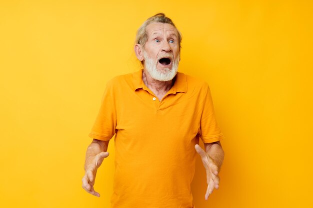 Portrait of happy senior man yellow shirt posing emotions yellow background. High quality photo