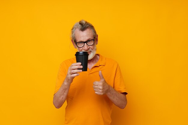 Portrait of happy senior man in a yellow Tshirt a glass with a drink cropped view